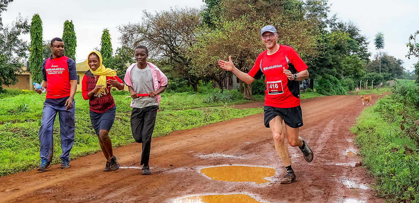 A group of people run down a dirt road.