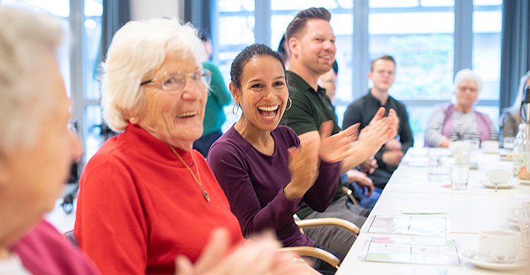 A group of people clap at a table.