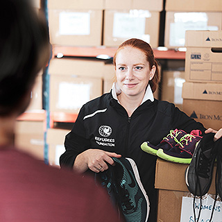 A woman stands in a warehouse with boxes full of shoes.