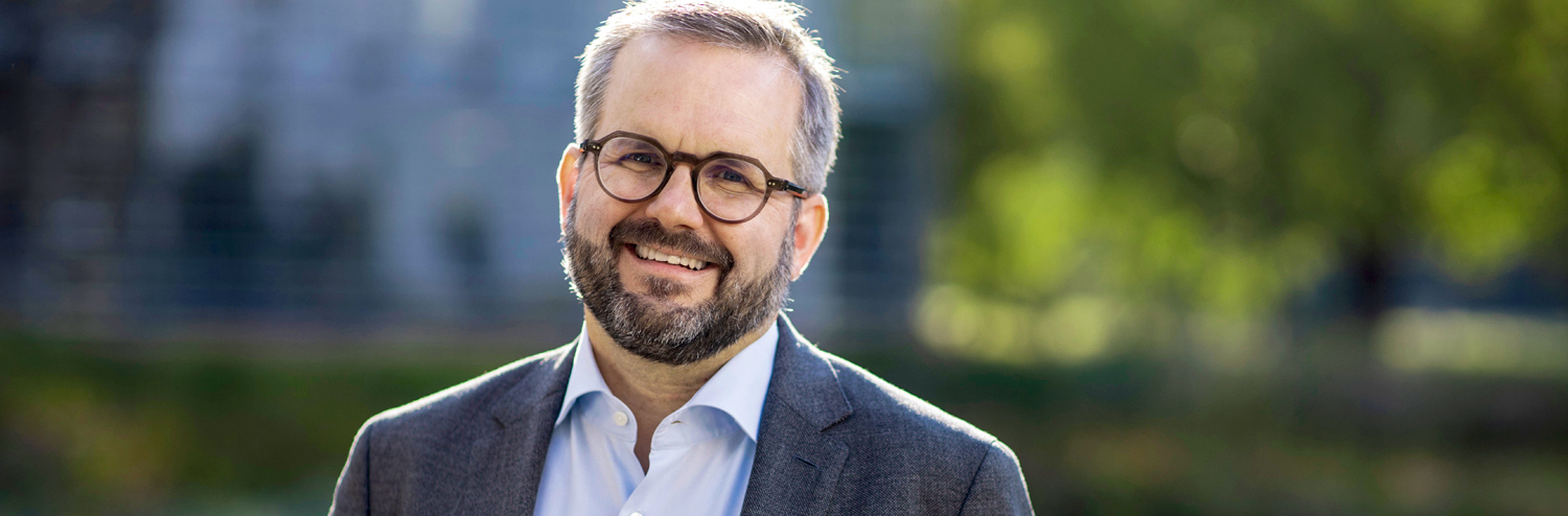 A man with glasses and a beard is smiling.