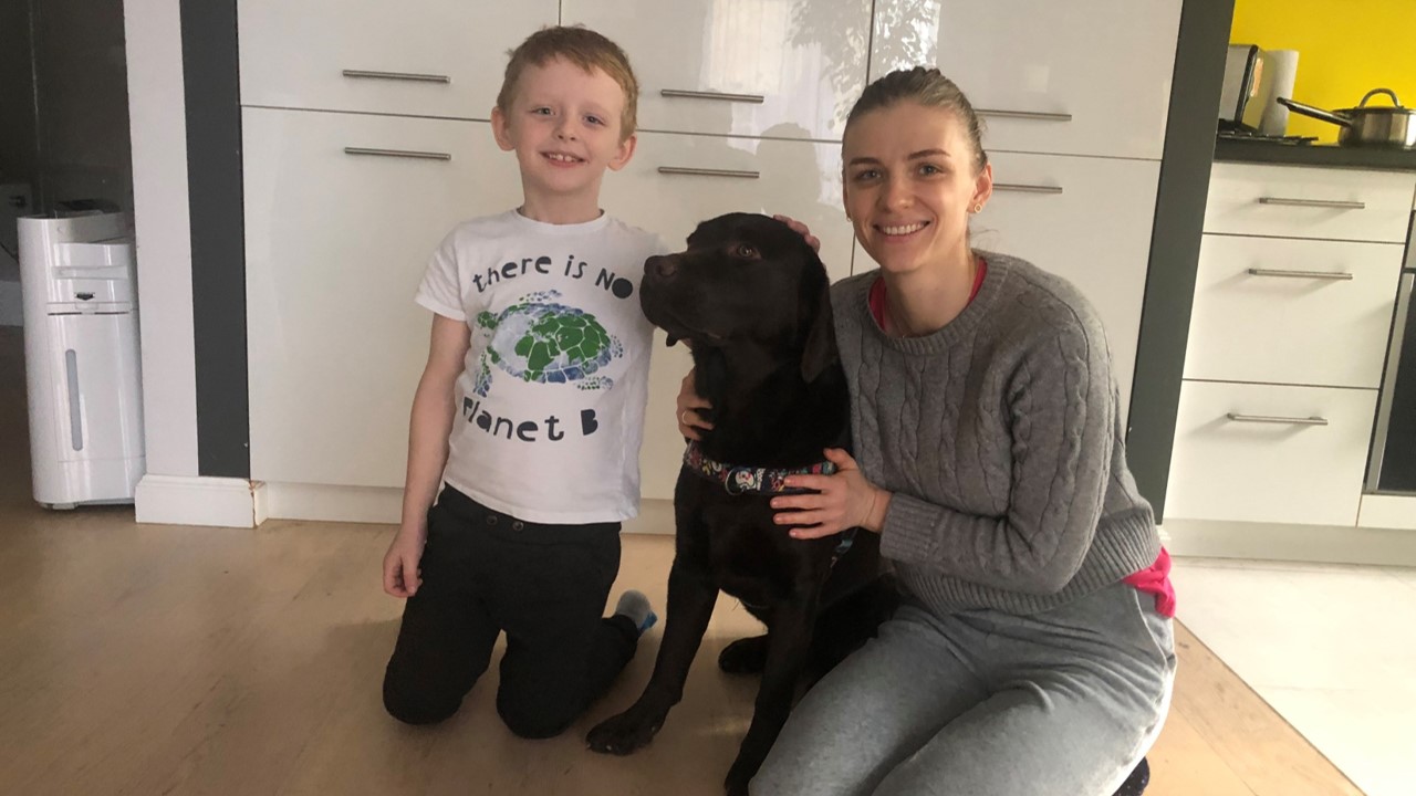 A woman and a young boy in a living room with a dog 