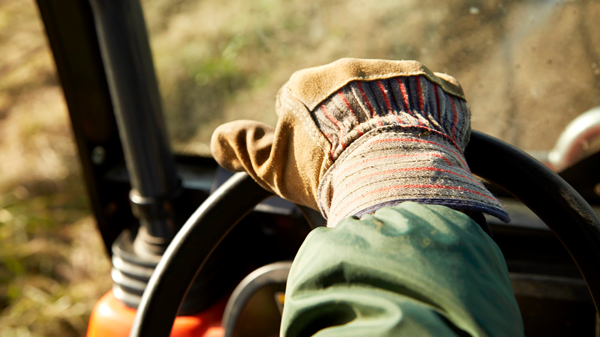 Farmer with hand on tractor wheel