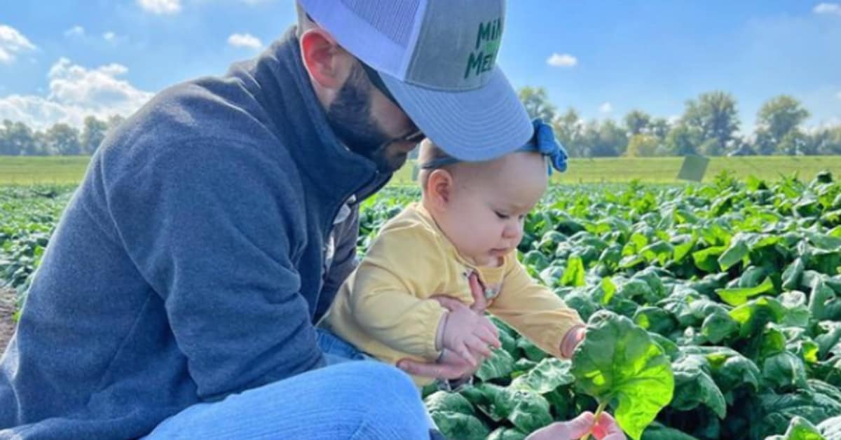 A person holding a baby in a field