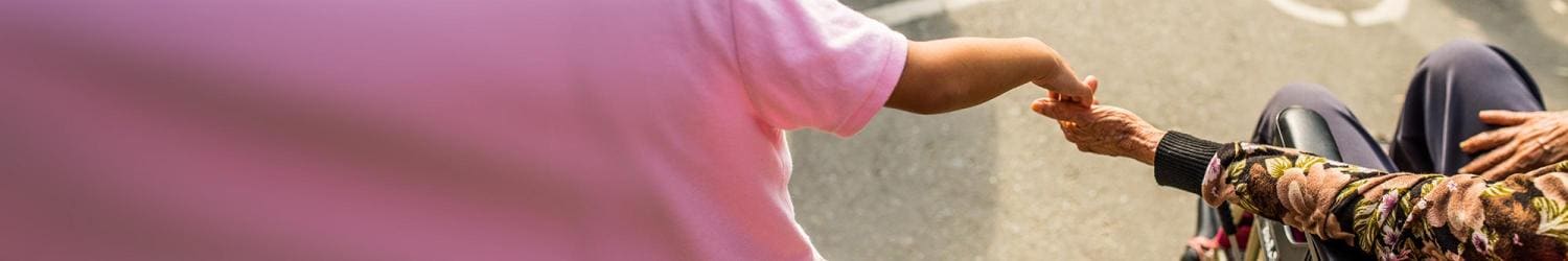 A woman in a pink shirt shakes someone's hand.