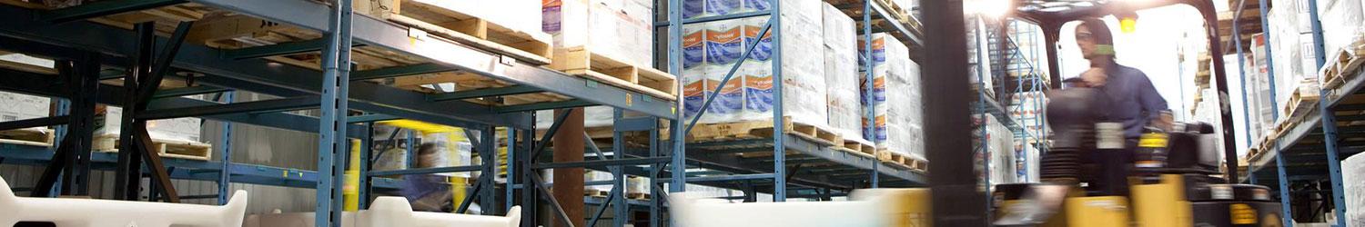 A forklift is driving through a warehouse full of pallets.