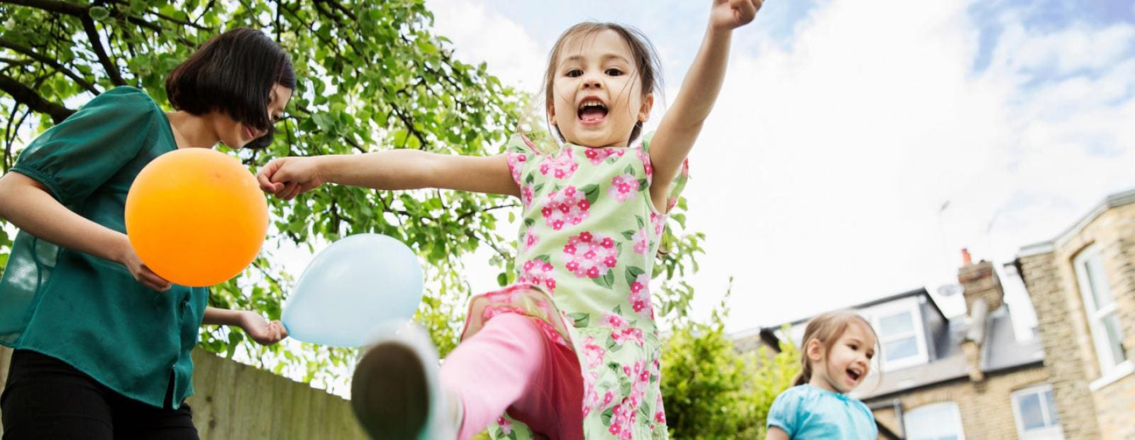 A young girl is playing with balloons in a backyard.