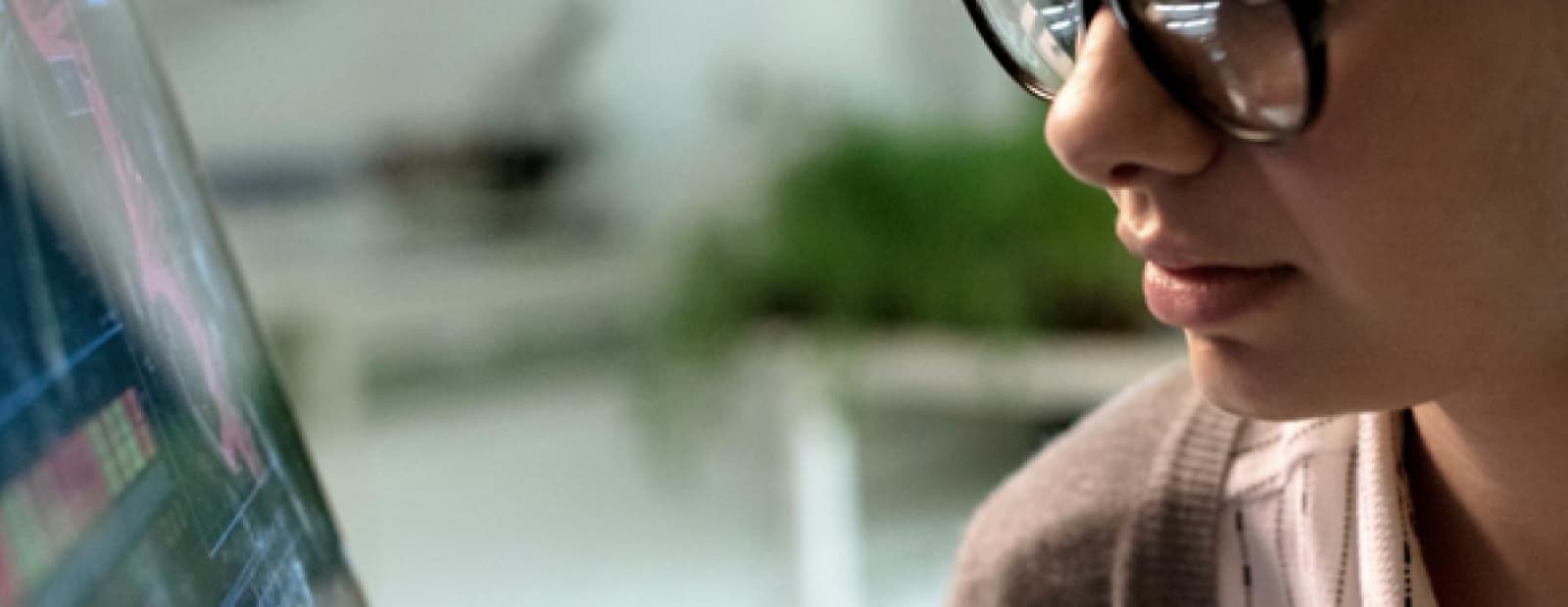 A woman wearing glasses is looking at a computer screen.