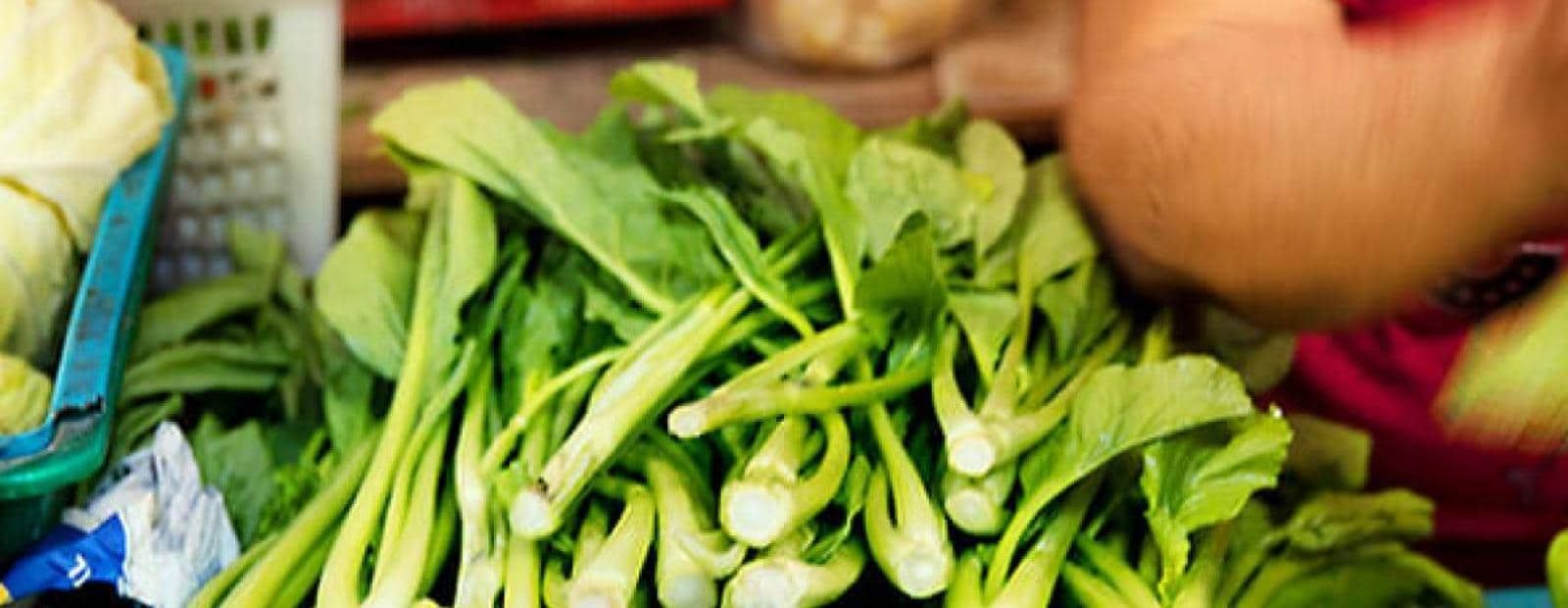 A man is preparing vegetables at a market.