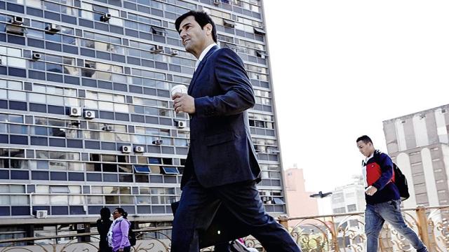 A man in a suit walks down a city street.