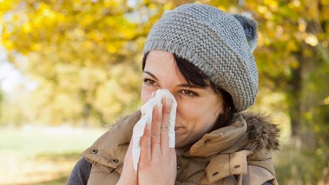 A woman blowing her nose with a tissue.