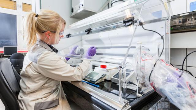 A woman working in a lab with a microscope.