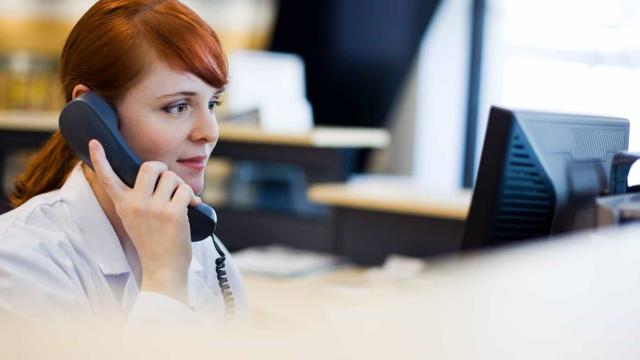 A woman talking on the phone in front of a computer.