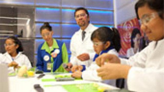 A group of people in lab coats preparing food.