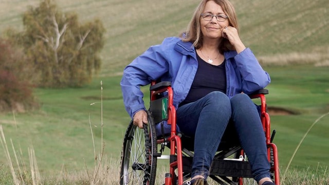 A woman in a wheelchair sitting in a field.