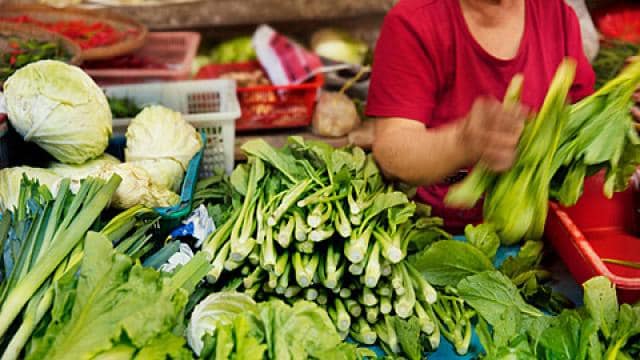 A woman is buying vegetables at a market.