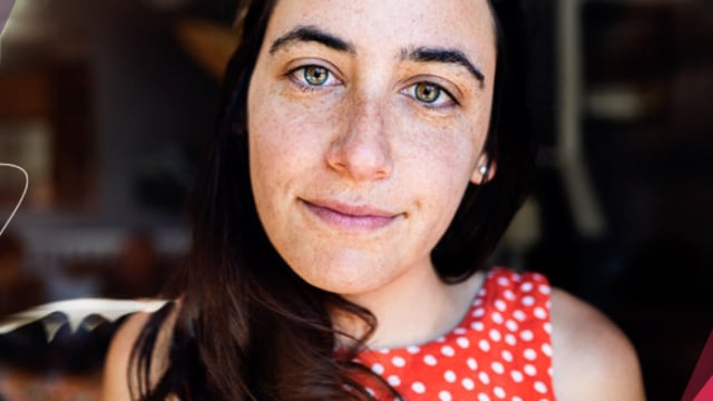 A woman's face is shown with a pink background.