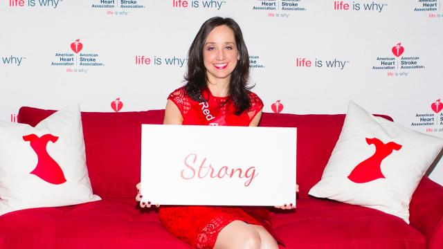 A woman sitting on a red couch holding a sign.