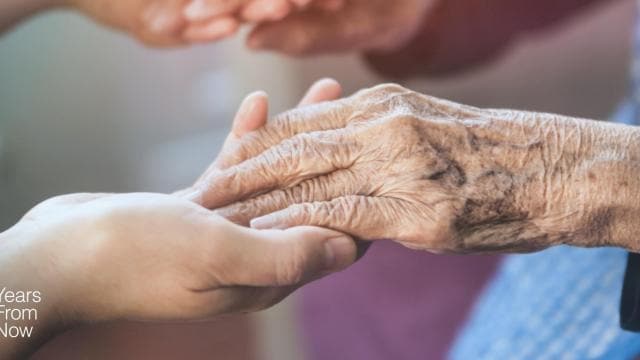 An elderly woman is holding an elderly woman's hand.