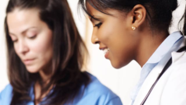 Two female nurses talking to each other on a laptop.