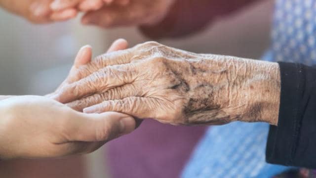 A woman is holding an elderly woman's hand.