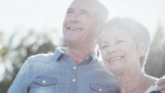 An older couple smiling in the sun.