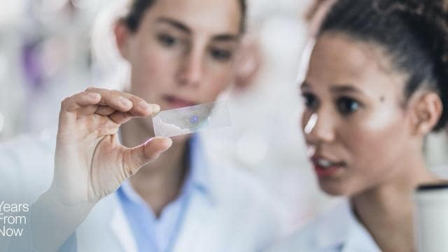 Two women in lab coats looking at a piece of paper.