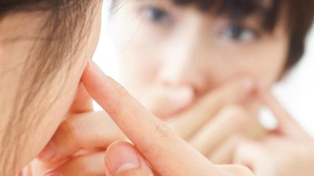 A woman is touching her face with her finger.