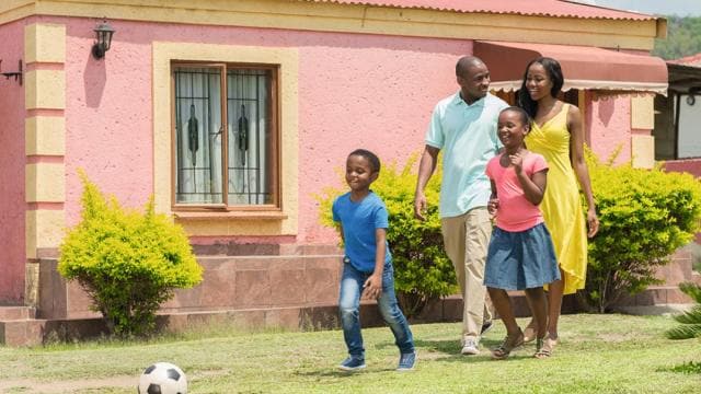 A family playing soccer in front of a pink house.