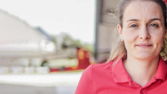 A woman in a red shirt standing in front of a building.