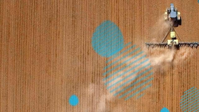 A tractor is spraying a field with blue dots.