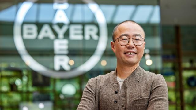 employee in front of a bayer cross