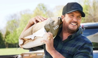 Luke Bryan carrying a DEKALB seed bag