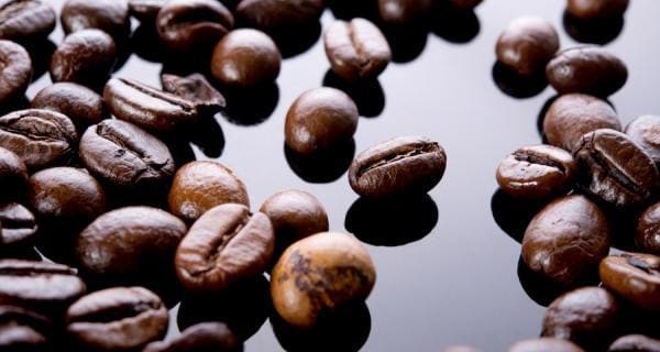 A close up of coffee beans on a black surface.