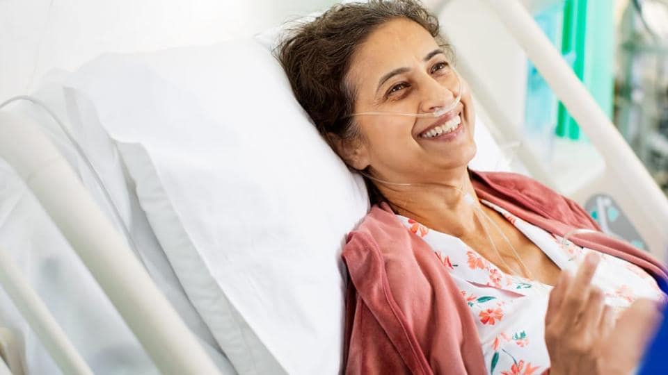 A woman in a hospital bed smiling.