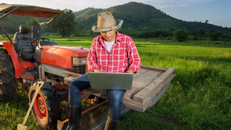 A man sitting on a tractor with a laptop.