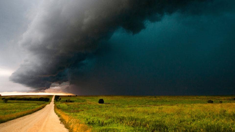 A dark cloud is seen over a dirt road.