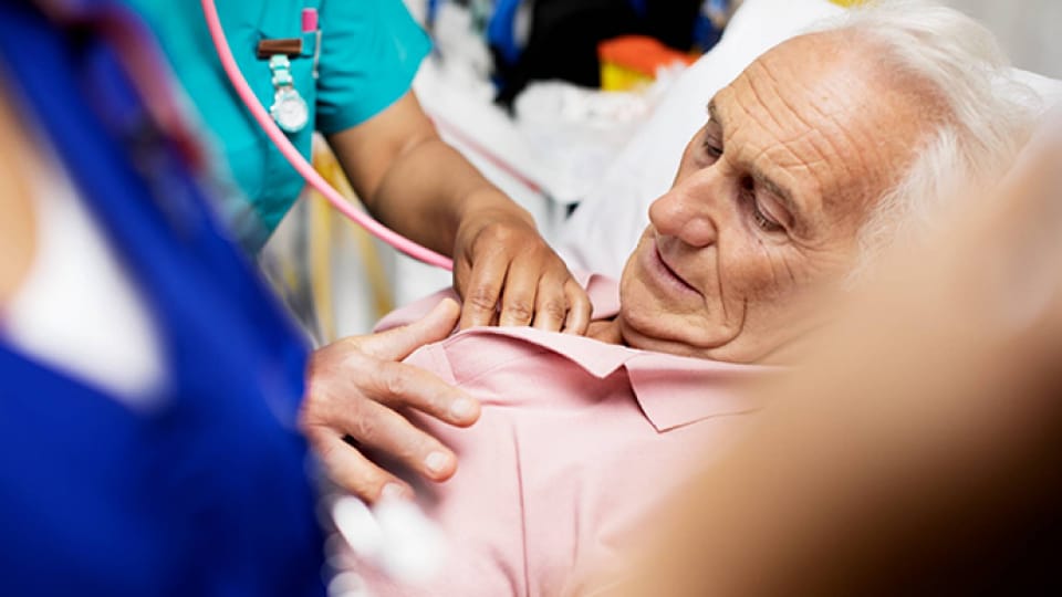 A nurse is touching an elderly patient's shoulder.