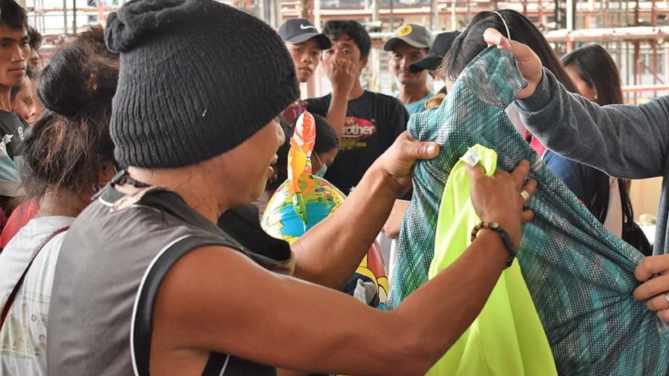 A man is handing a shirt to a group of people.