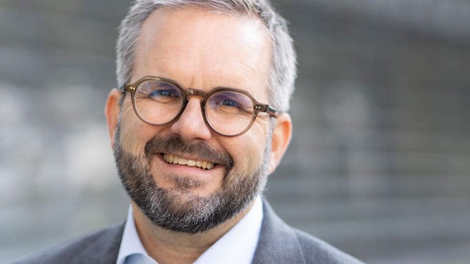 A man with glasses and a beard smiling for the camera.