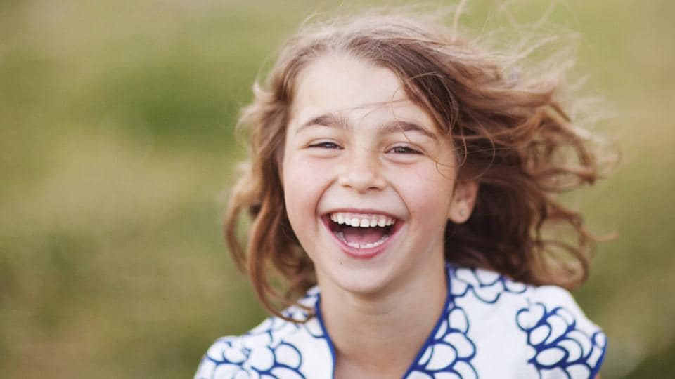 A young girl laughing in a field.