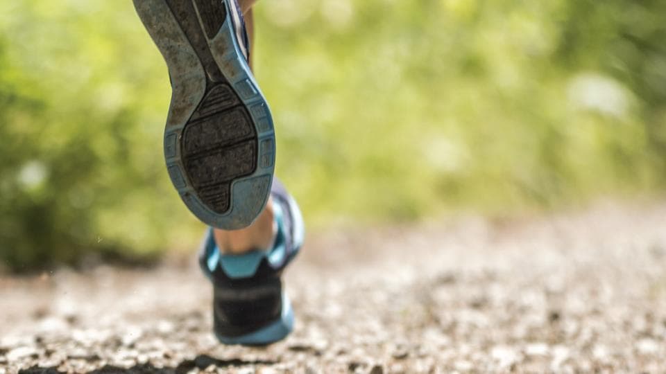 A close up of a person running on a dirt path.