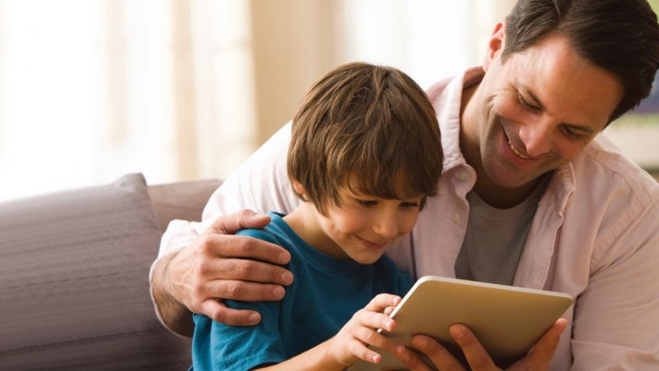 A man and a boy looking at a tablet computer.