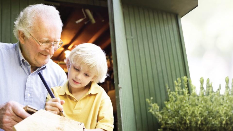 An older man and a young boy working on a piece of wood.