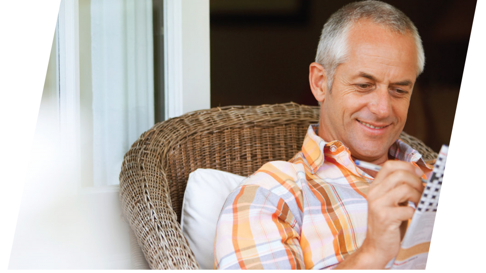 A man sitting in a wicker chair reading a book.