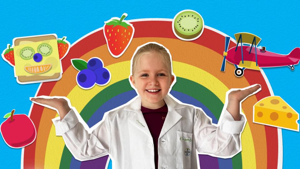 A young boy in a lab coat is standing in front of a rainbow.