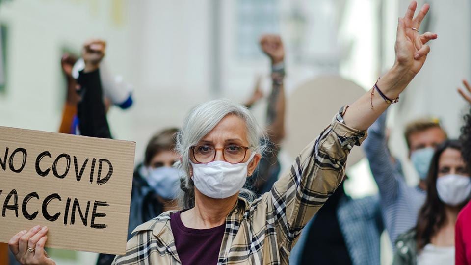 A group of people holding signs that say no covid vaccine.