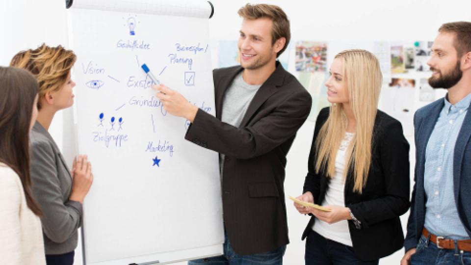 A group of people standing around a whiteboard.