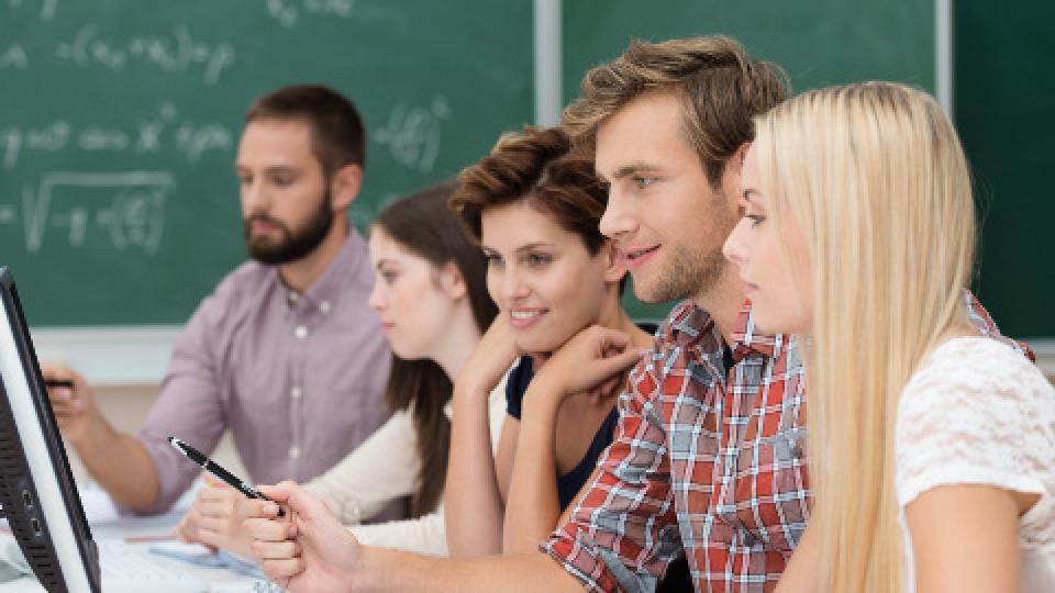 A group of people sitting in front of a computer.