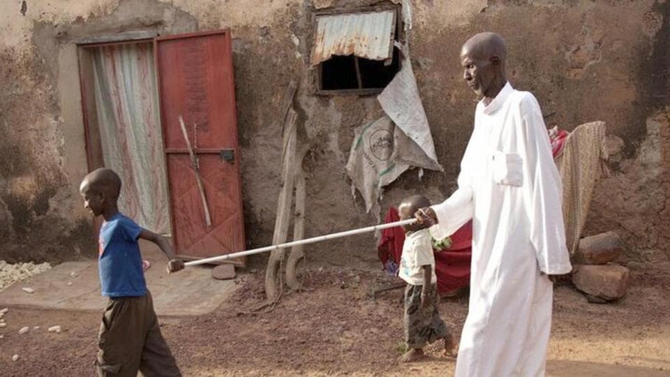 A man is holding a stick in front of a house.