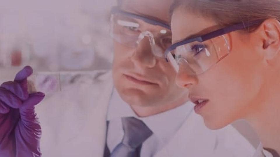 A man and woman in lab coats are looking at something.